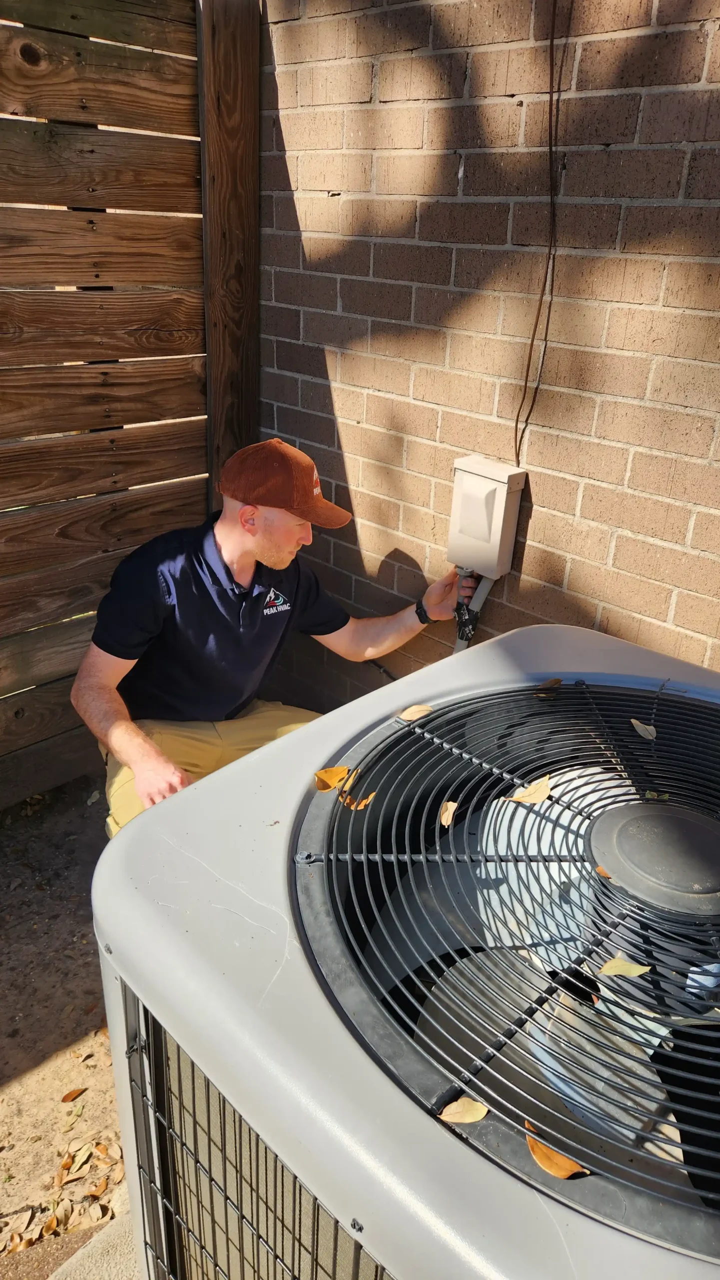Peak HVAC technician working on residential outdoor HVAC equipment